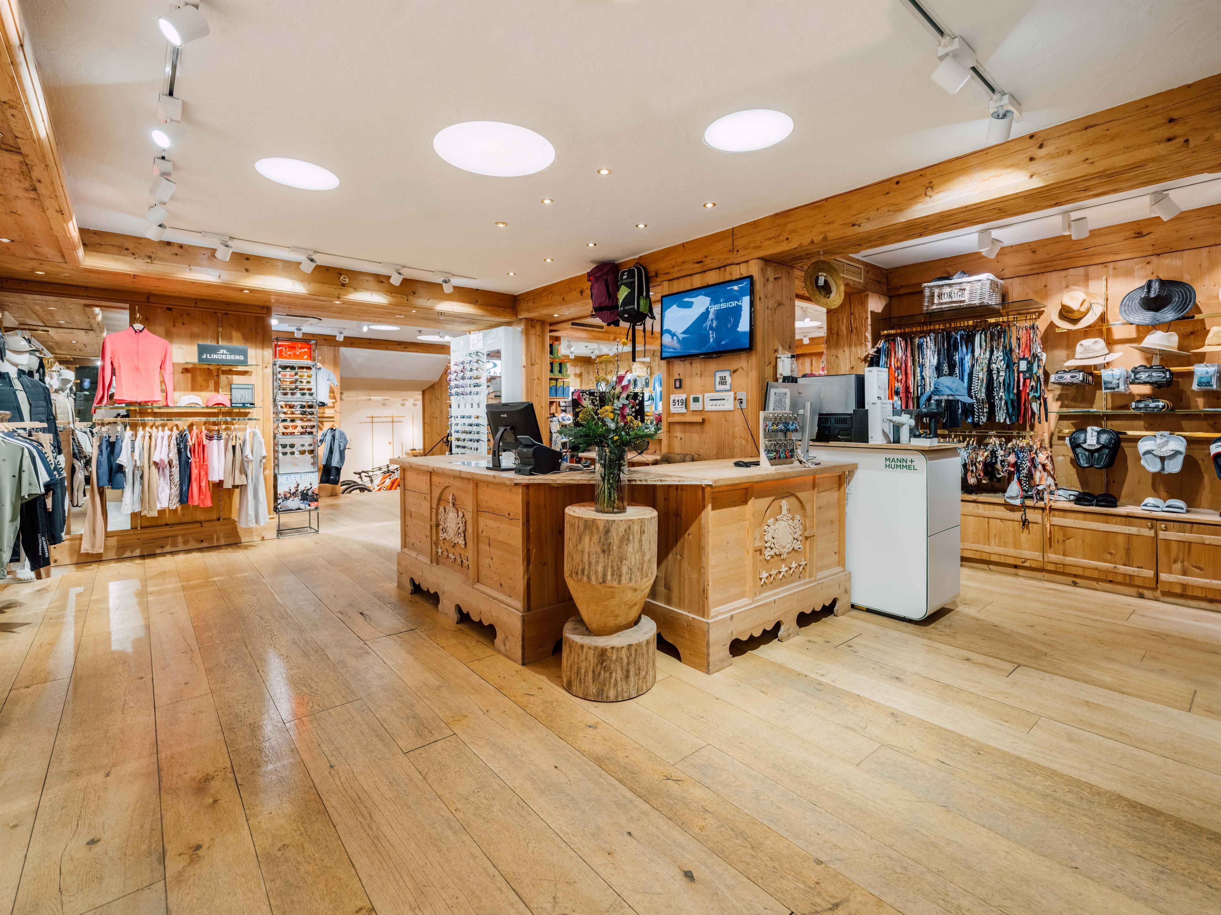 Ein moderner Sportbekleidungsladen mit Holzinterieur. Verschiedene Kleidungsstücke und Accessoires sind ordentlich ausgestellt.