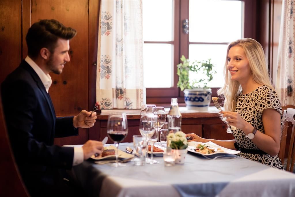 Ein romantisches Abendessen in einem gemütlichen Restaurant. Ein Mann und eine Frau genießen ihr Essen und trinken Wein bei romantischem Licht.