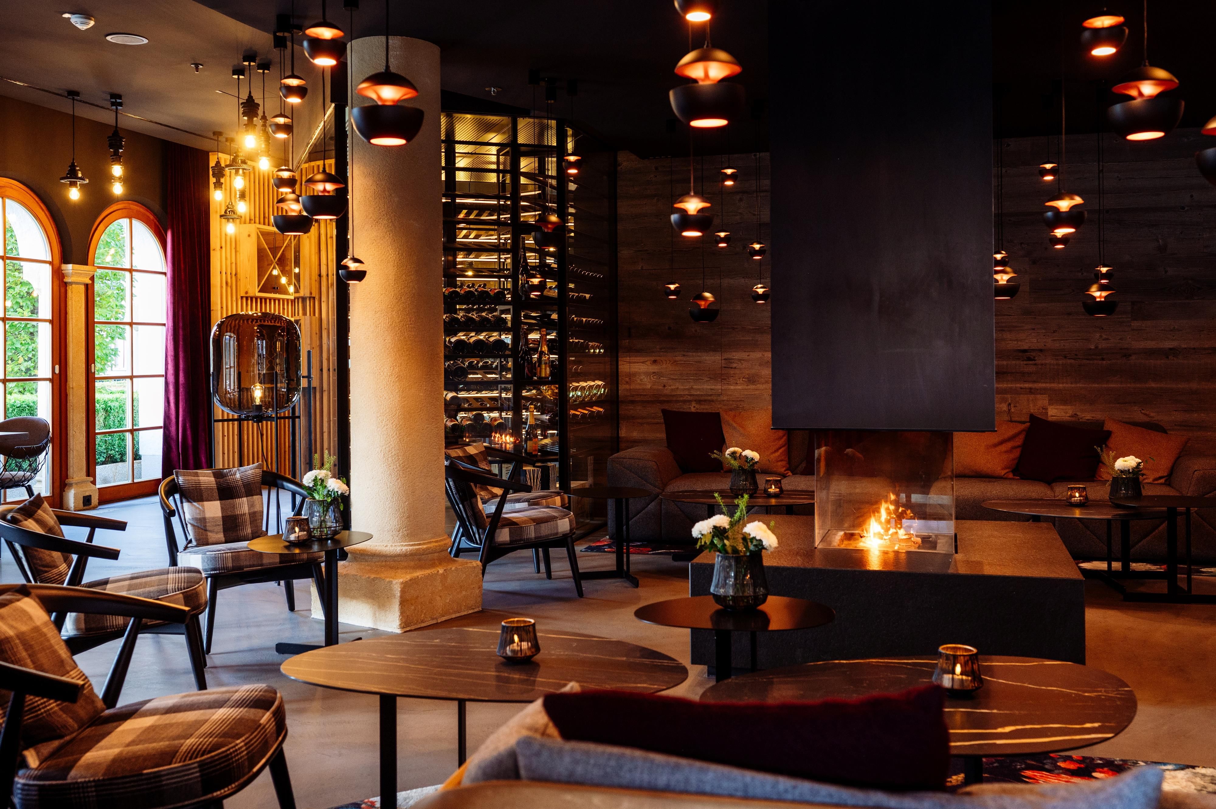 Ein gemütlicher Innenraum mit stilvollen Möbeln und sanfter Beleuchtung. Der Raum verfügt über einen Kamin und eine Weinsammlung.