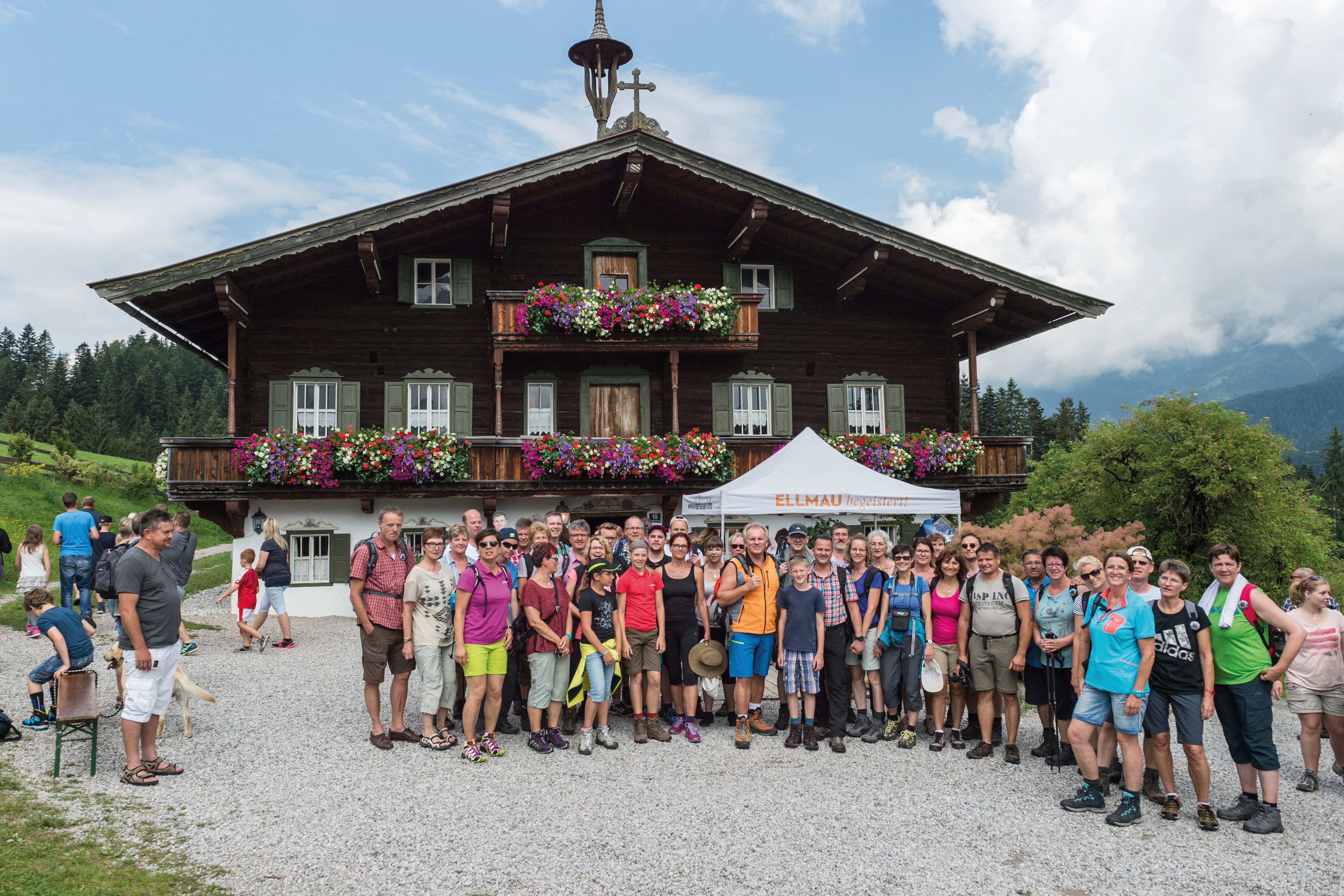 Gruppe vor dem Bergdoktorhaus, altes Holzhaus mit Blumenbalkons