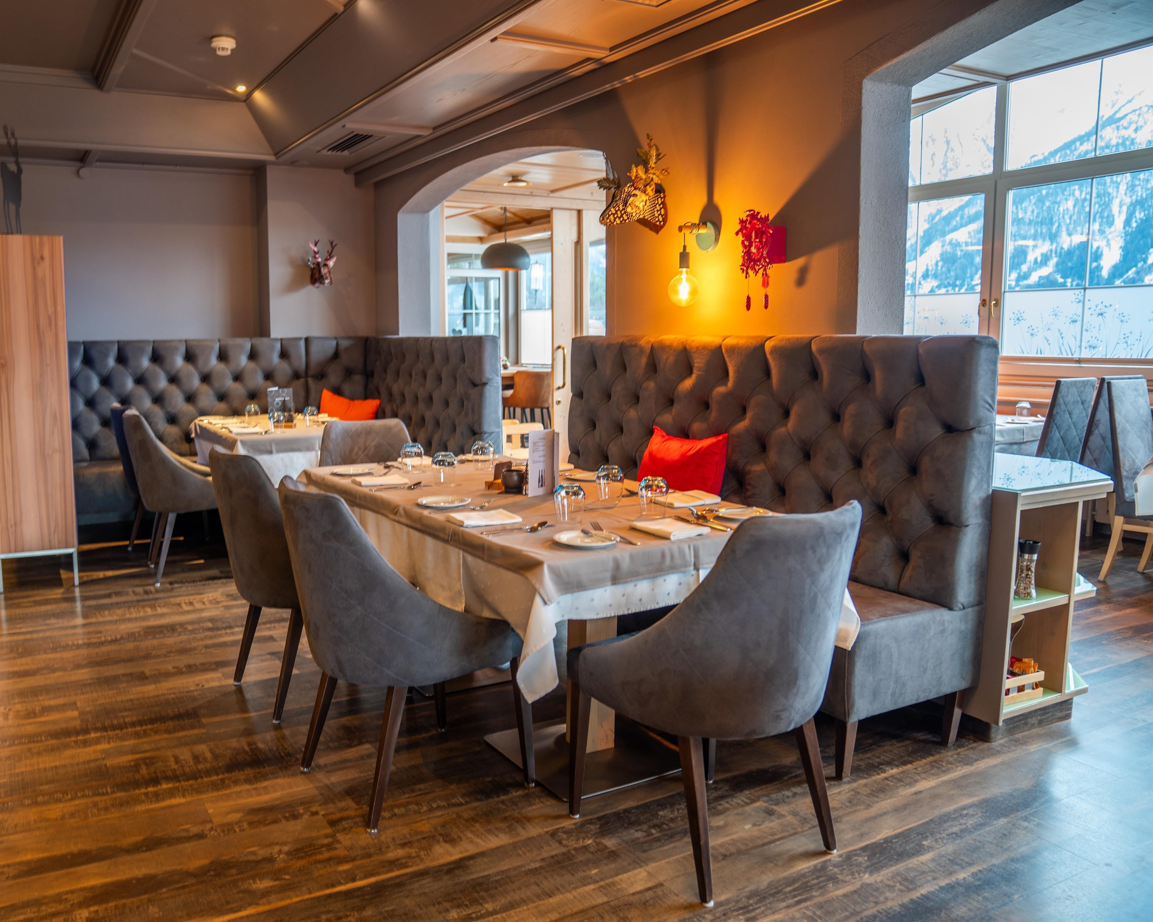 Ein gemütliches Restaurant mit eleganten Sitzgelegenheiten und einem gut eingedeckten Tisch. Die warme Beleuchtung schafft eine einladende Atmosphäre.