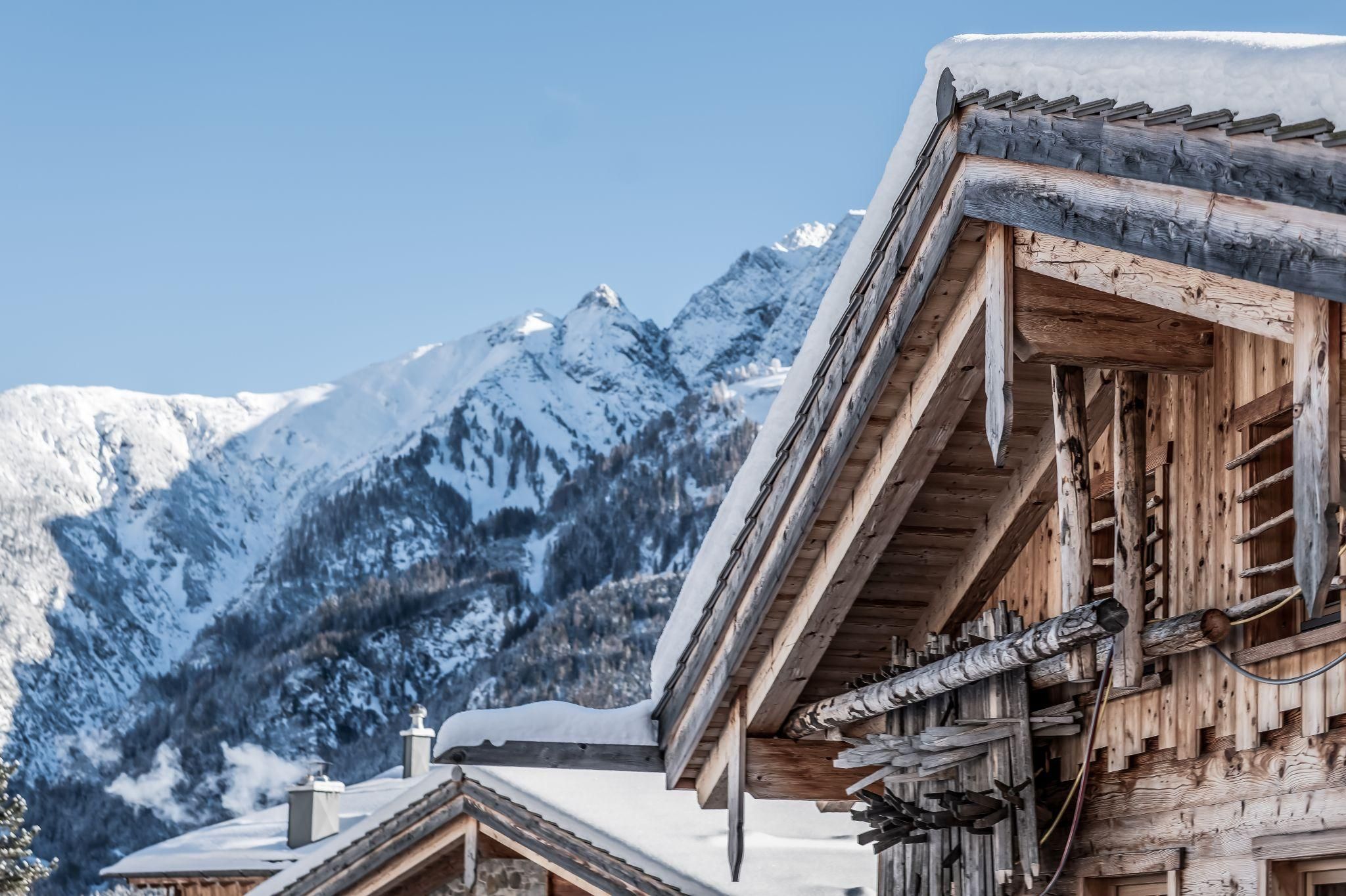 Eine idyllische Berglandschaft mit schneebedeckten Gipfeln und Chalet. Der klare Himmel ergänzt die winterliche Atmosphäre.