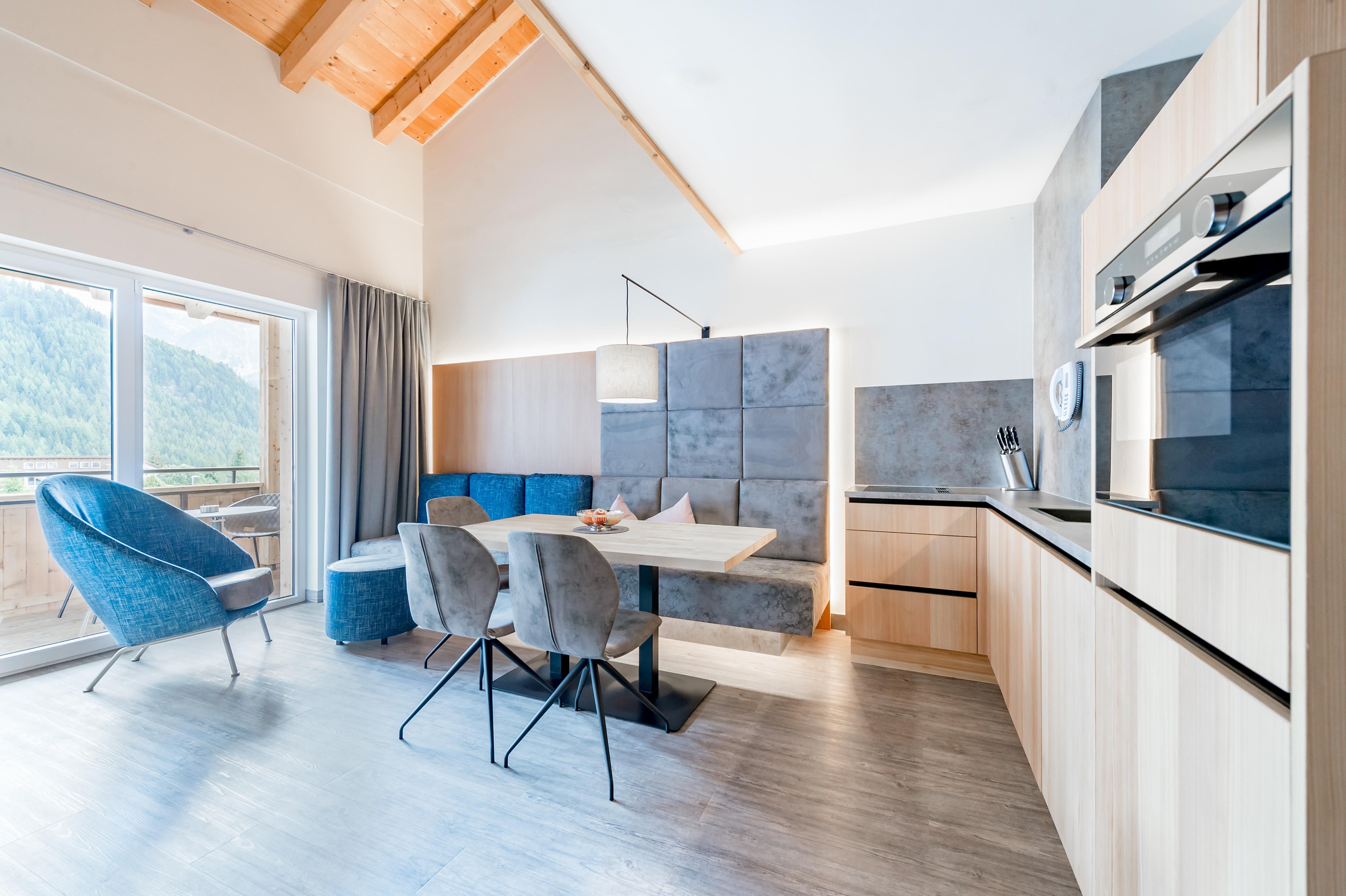 Eine moderne Küchen- und Essbereich mit hellen Holzelementen und einem großen Fenster. Der Raum ist stilvoll eingerichtet und bietet eine gemütliche Atmosphäre.