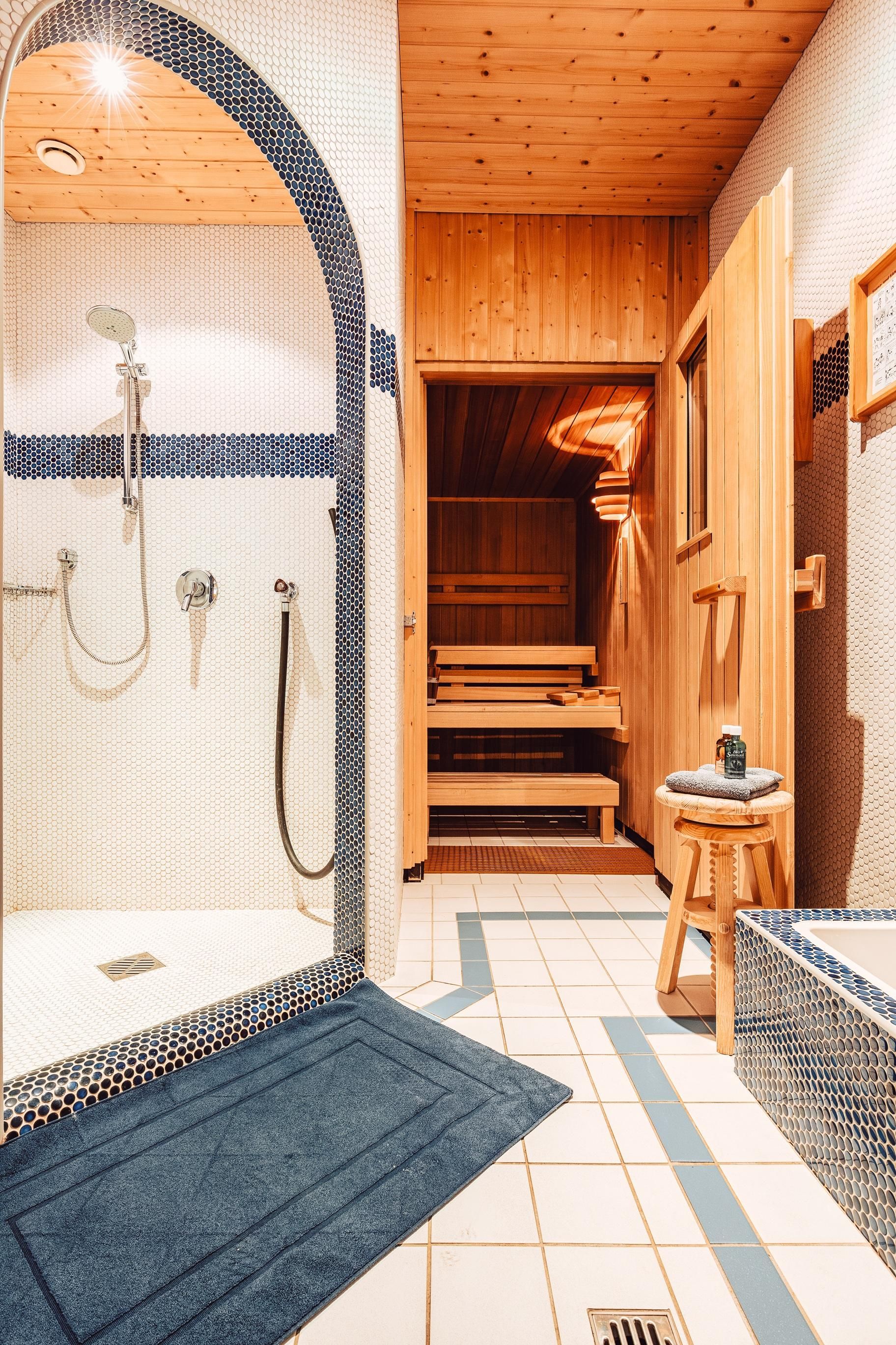 Ein modernes Badezimmer mit einer Dusche und einer Sauna. Die Holzdecke und der Fliesenboden schaffen eine entspannende Atmosphäre.