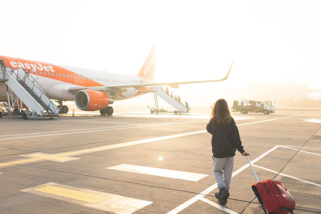 Mädchen mit Koffer steigt in Easy Jet Flugzeug am Flughafen Innsbruck ein
