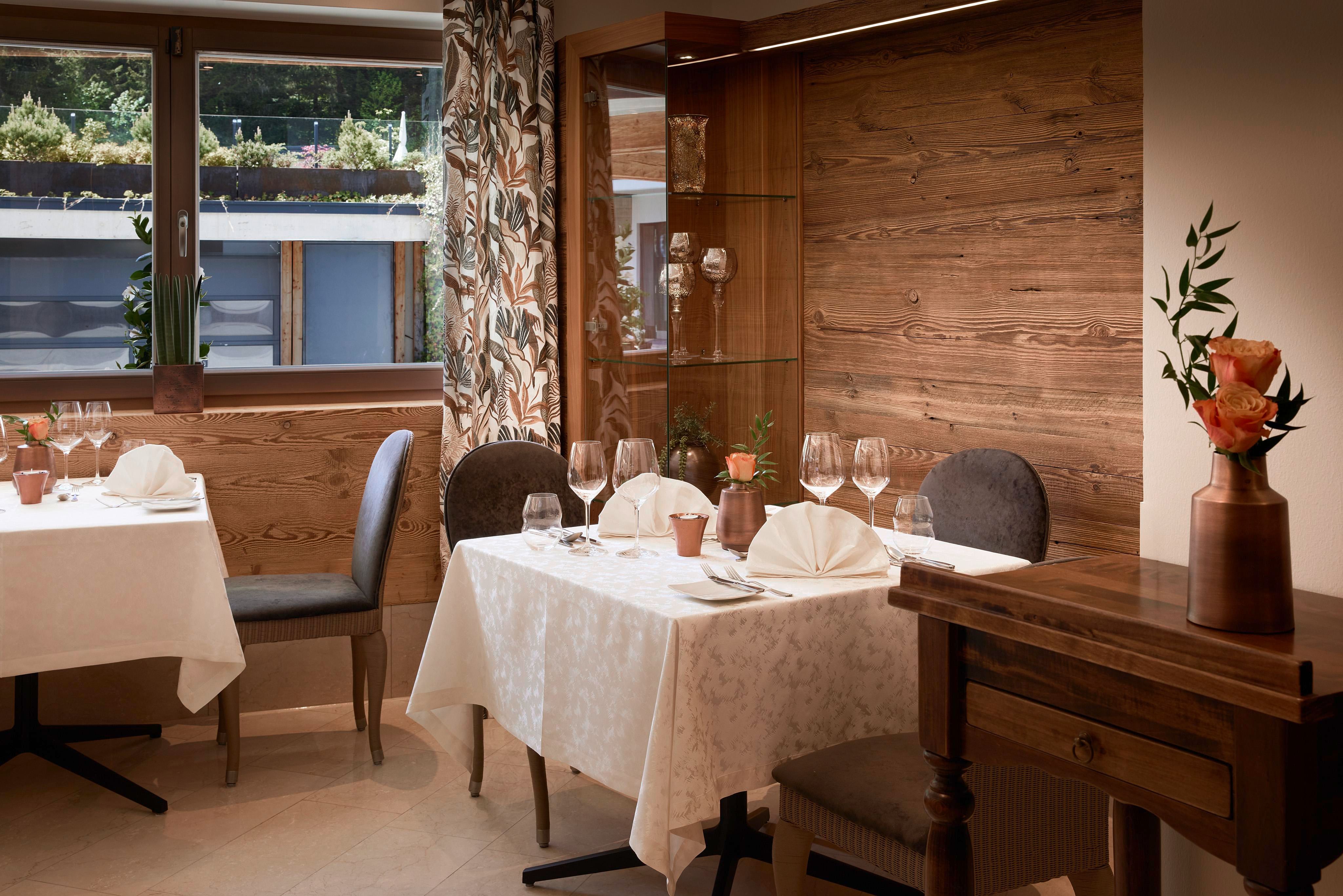 Ein elegantes Restaurant mit gedeckten Tischen und stilvoller Einrichtung. Große Fenster sorgen für viel Licht und eine angenehme Atmosphäre.