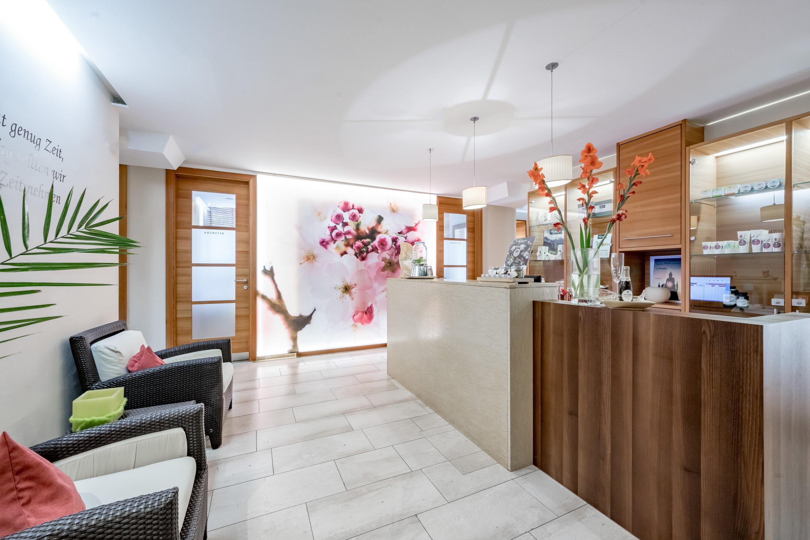 Ein moderner Empfangsbereich mit freundlicher Ausstattung. Die Wände sind geschmückt mit Blumenmotiven und es gibt bequeme Sitzgelegenheiten.