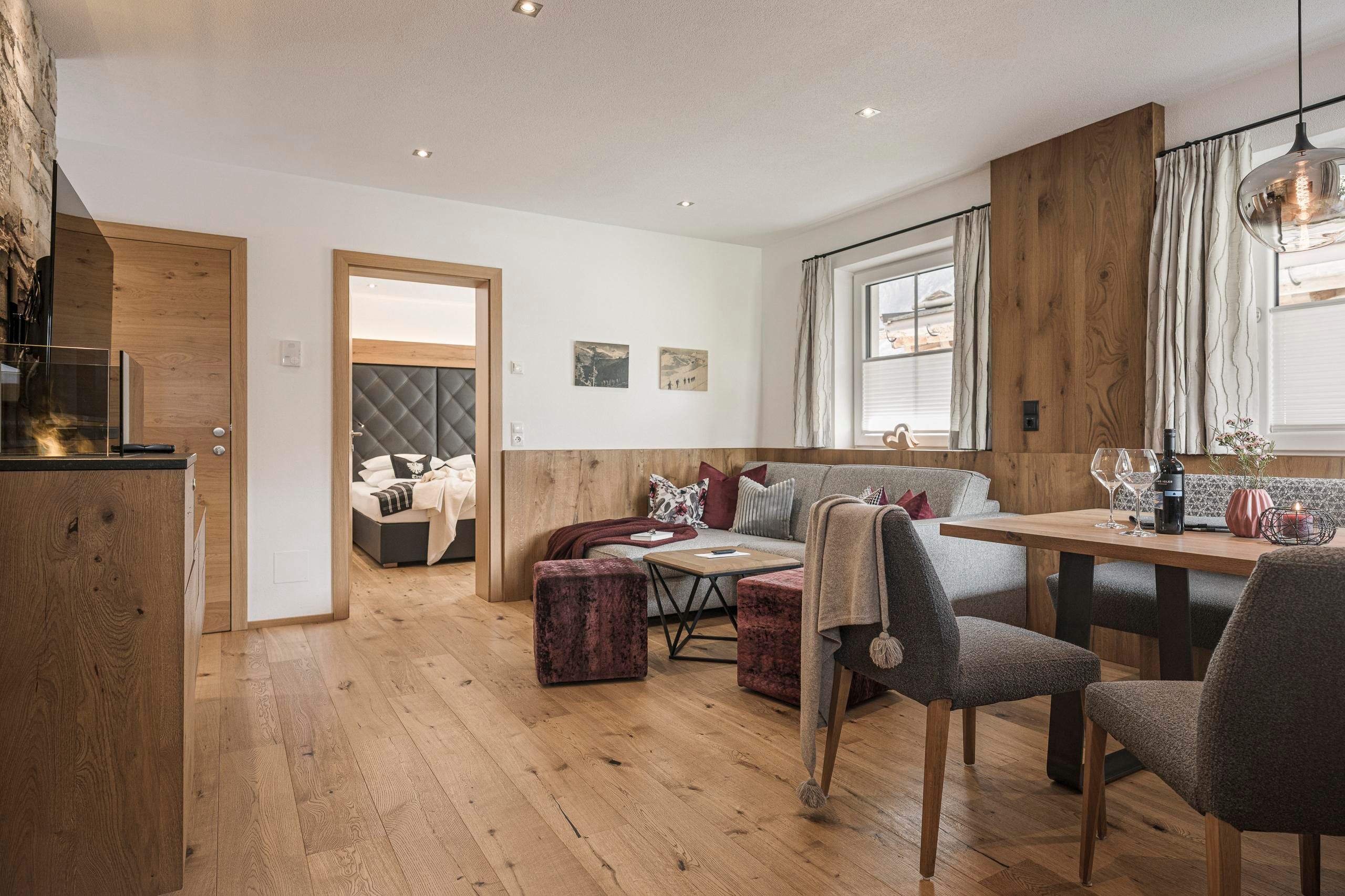 Ein modernes Wohnzimmer mit Holzfußboden und stilvoller Einrichtung. Im Hintergrund ist ein gemütlicher Schlafbereich zu sehen.