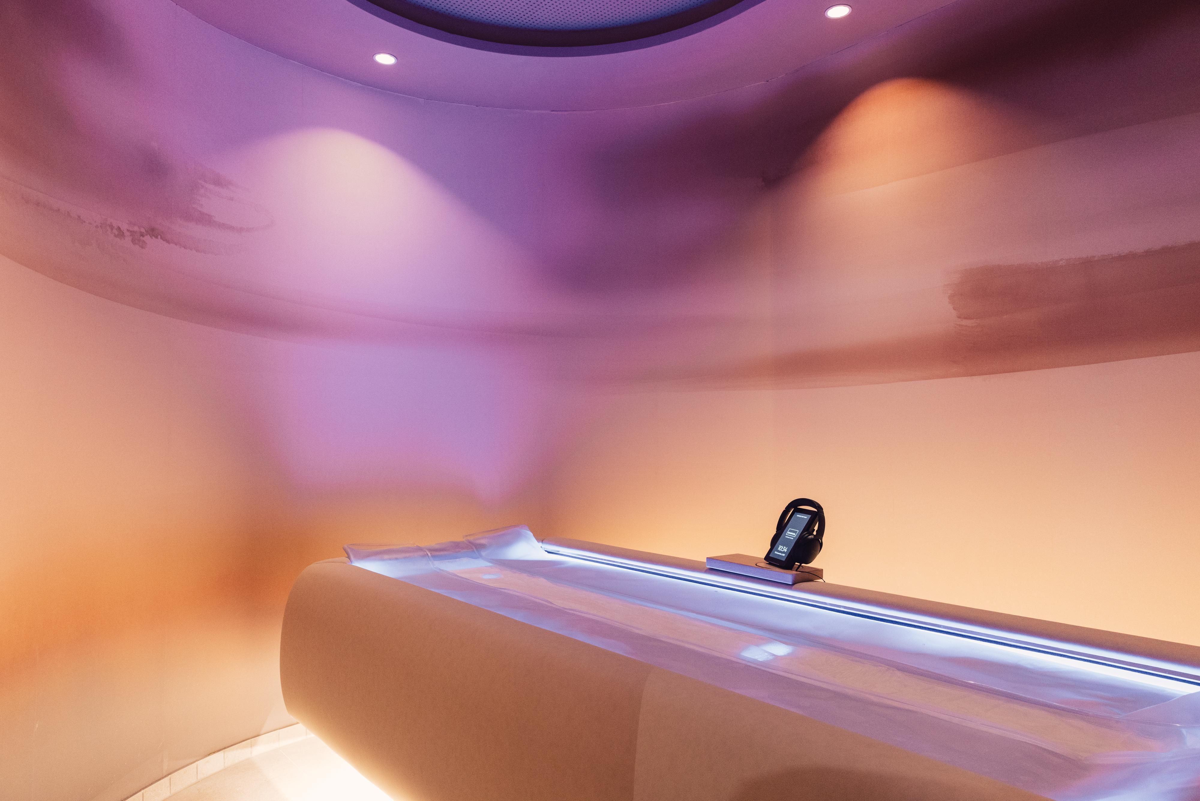 Ein modernes Spa mit sanften Farben und warmem Licht. Im Mittelpunkt steht eine bequeme Liege, die zum Entspannen einlädt.