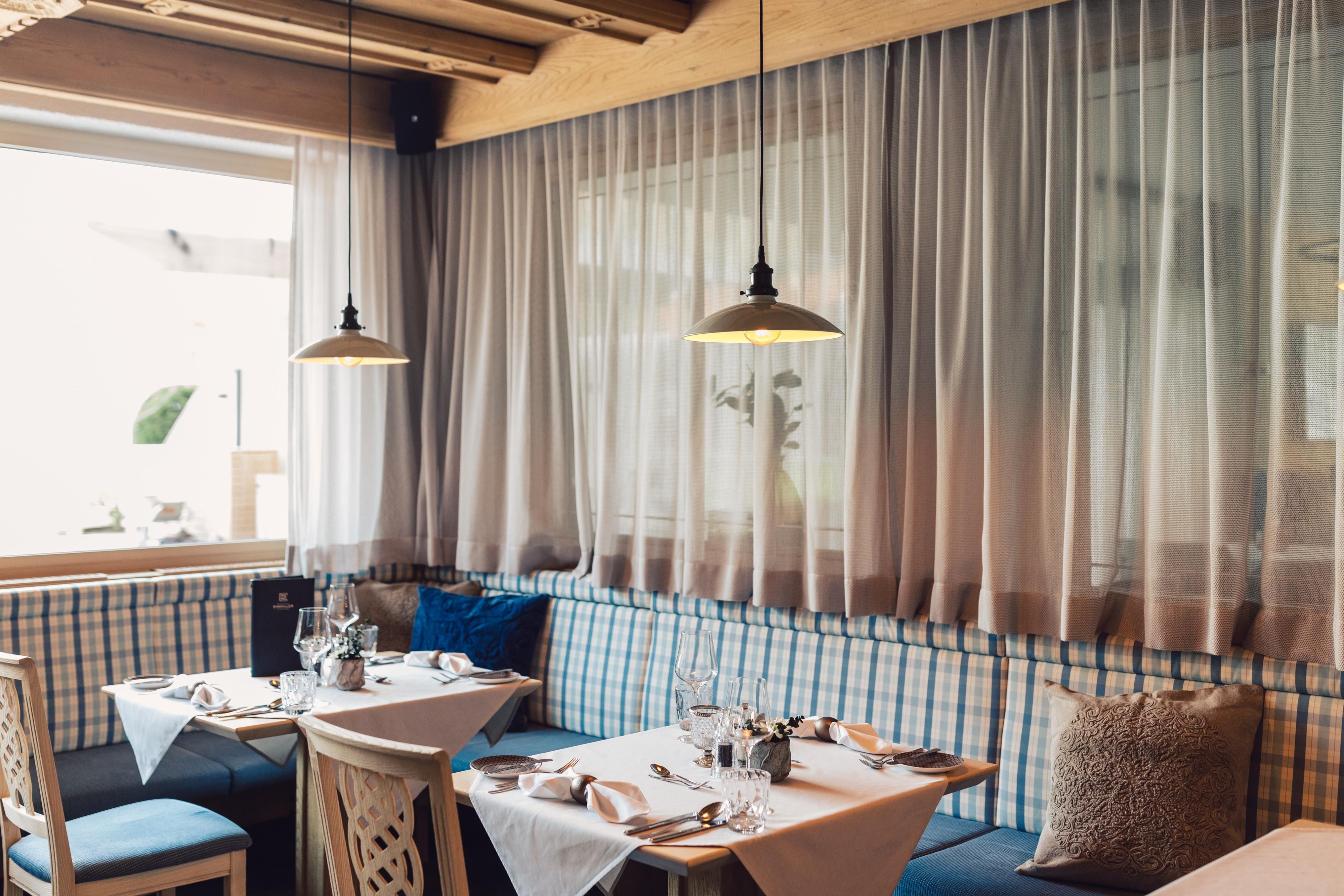 Ein gemütliches Restaurant mit hellen Fenstern und modernen Lampen. Die Tische sind stilvoll gedeckt mit Platz für mehrere Gäste.