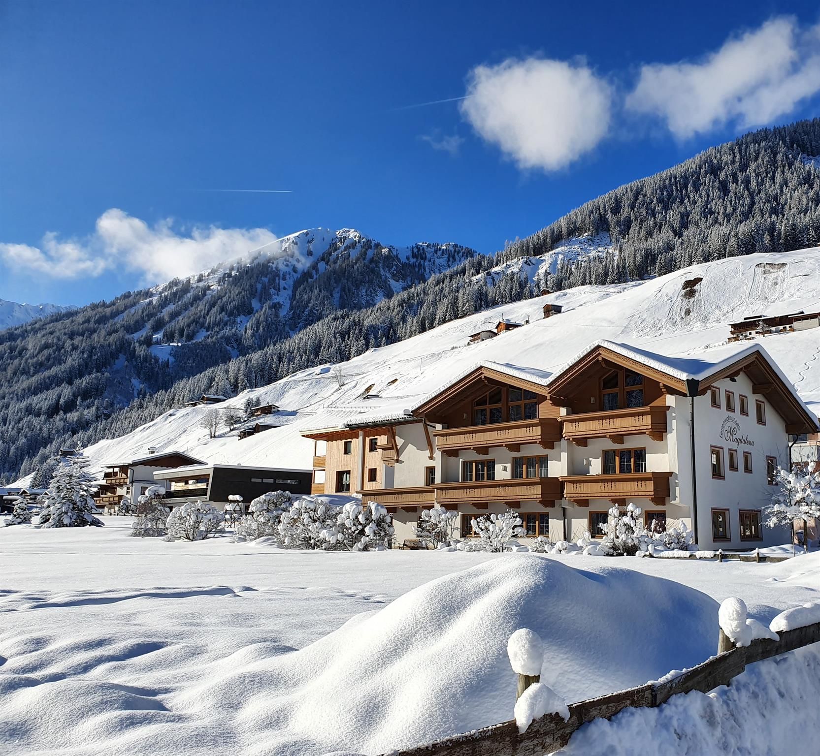 Eine malerische Winterlandschaft mit schneebedeckten Hügeln und einem gemütlichen Chalet. Die klare blaue Himmel und die verschneiten Bäume schaffen eine idyllische Atmosphäre.
