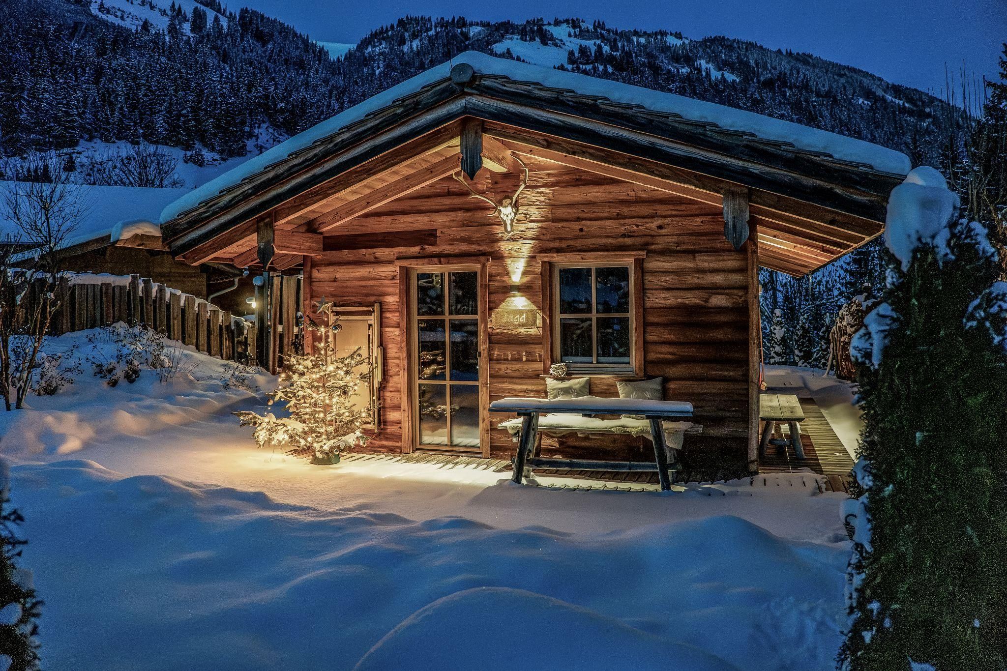 Ein gemütliches Chalet in der verschneiten Landschaft. Die Umgebung ist ruhig und der Himmel ist nachts zu sehen.