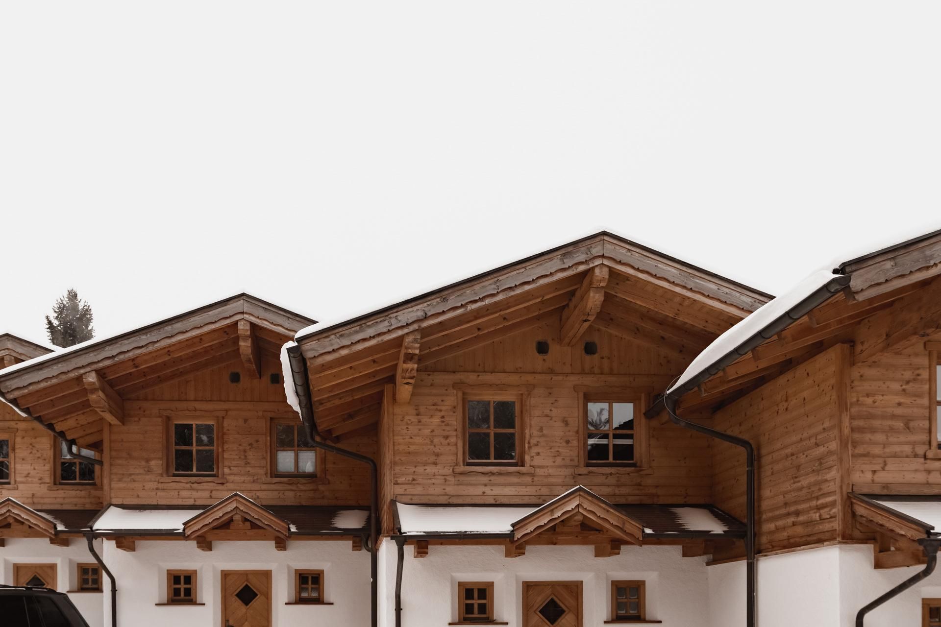 Eine Reihe von Holzchalets mit schneebedeckten Dächern. Die Fassaden sind traditionell gestaltet und strahlen Gemütlichkeit aus.