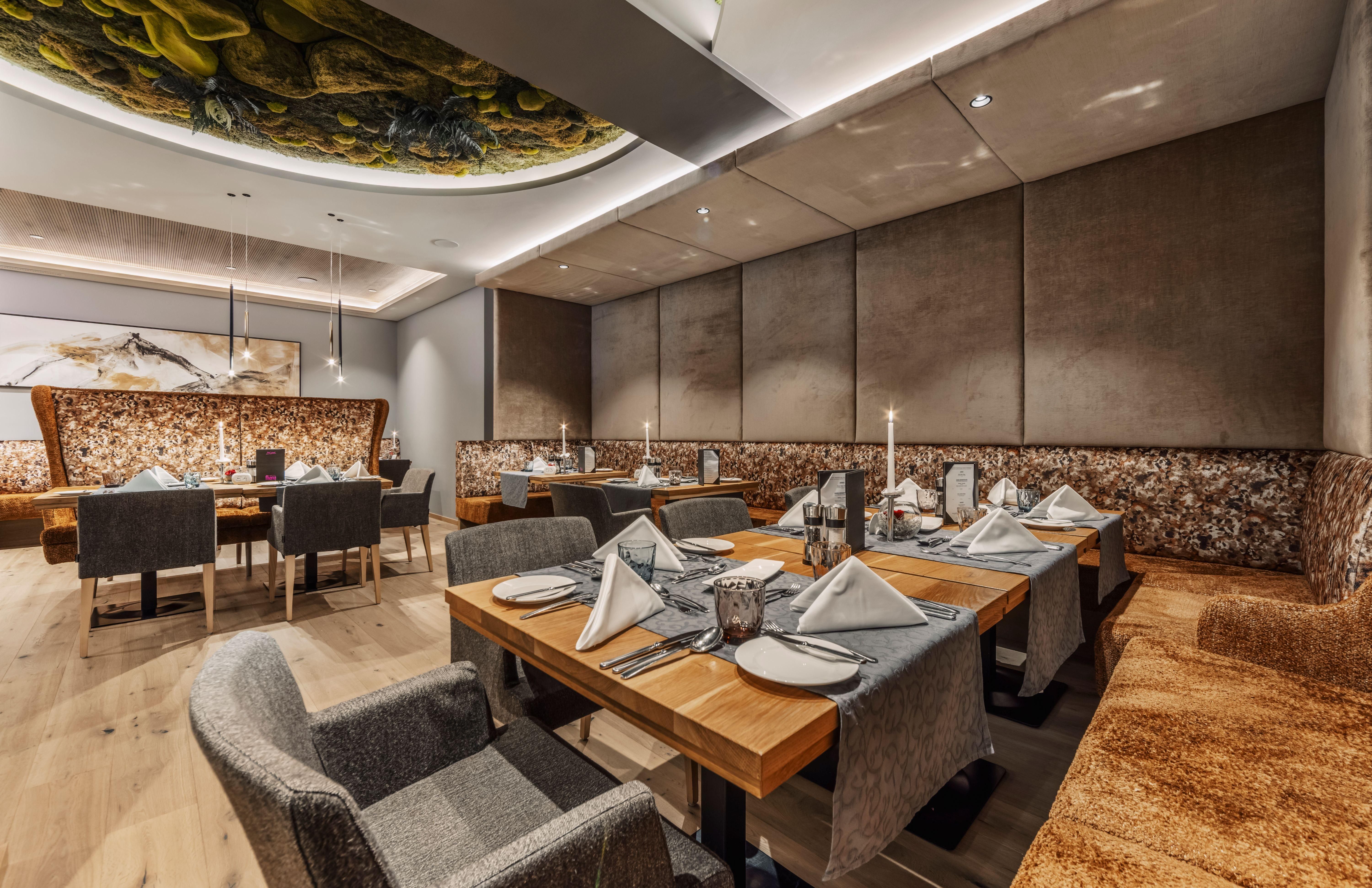 Ein elegantes Restaurant mit modernen Tischen und Stühlen. Die gedeckten Tische sind geschmackvoll dekoriert und schaffen eine einladende Atmosphäre.