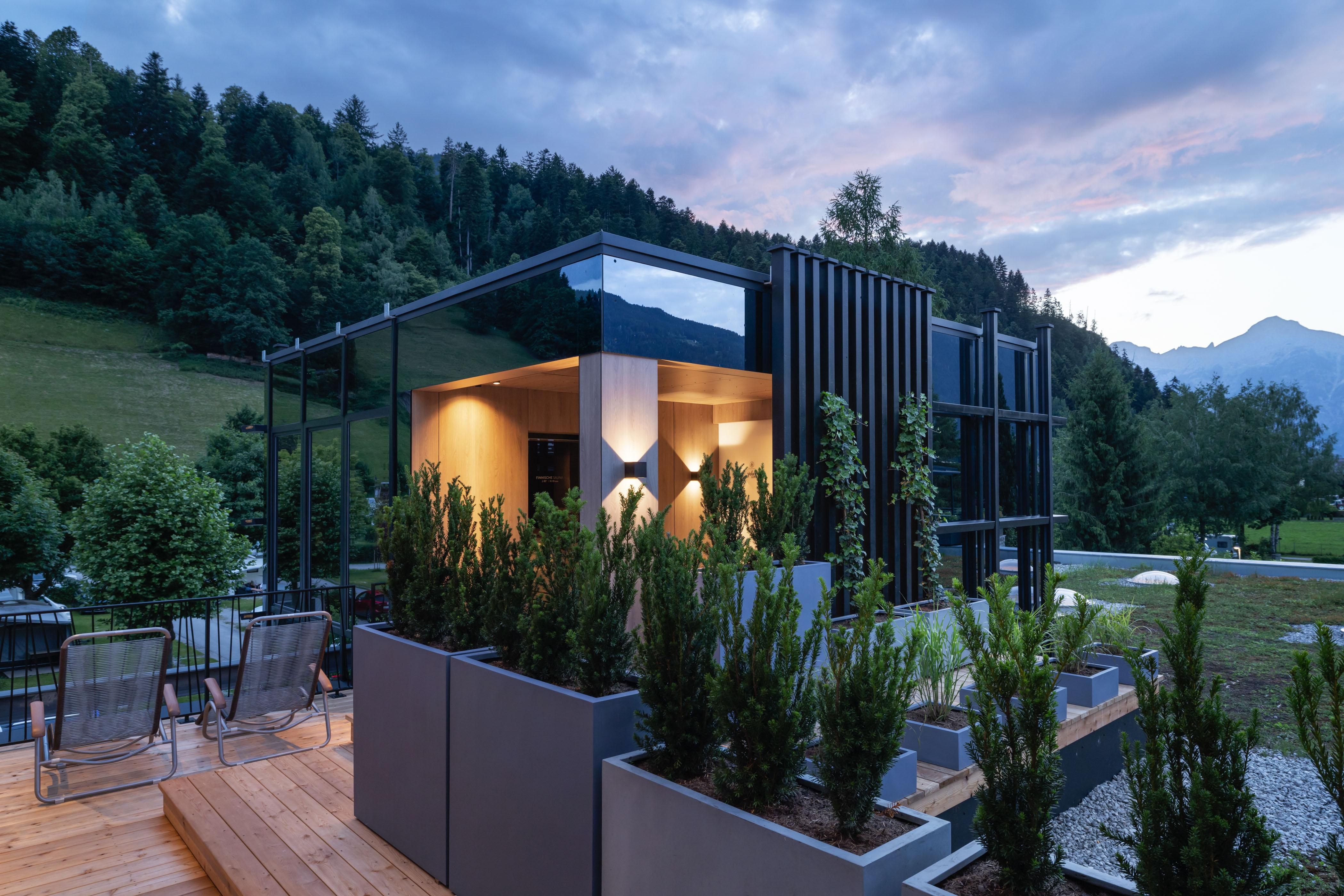 Ein modernes Haus mit großen Fenstern und einer modernen Architektur. Darüber hinaus sind es Gartenbereiche mit Pflanzen und Bäumen in einer landschaftlichen Umgebung.