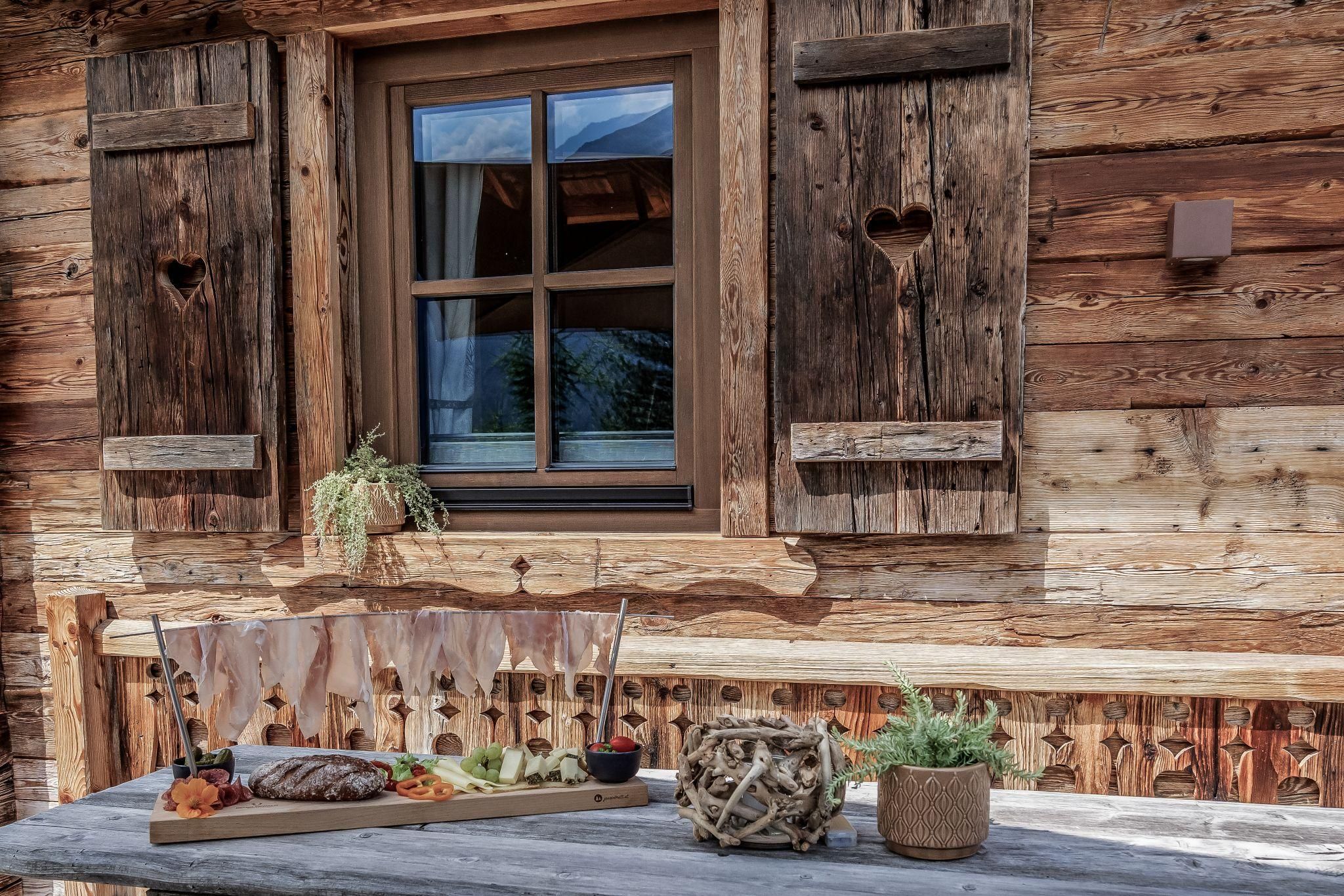 Ein gemütliches Chalet mit einer rustikalen Fensterbank. Auf dem Tisch stehen verschiedene dekorative Elemente und Pflanzen.