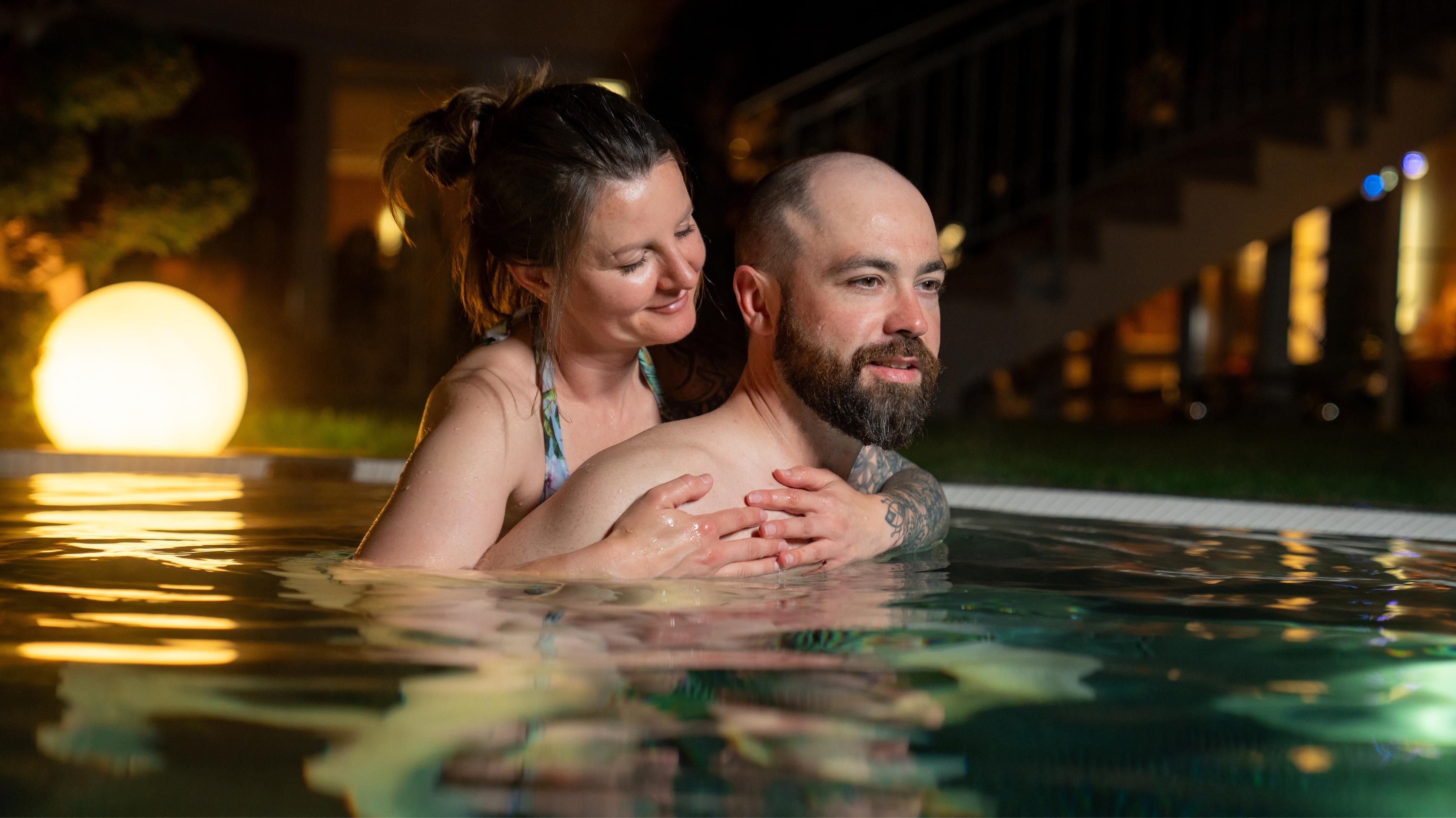 Ein Paar entspannt im Wasser eines Pools und genießt die gemeinsame Zeit. Die Atmosphäre ist warm und einladend.