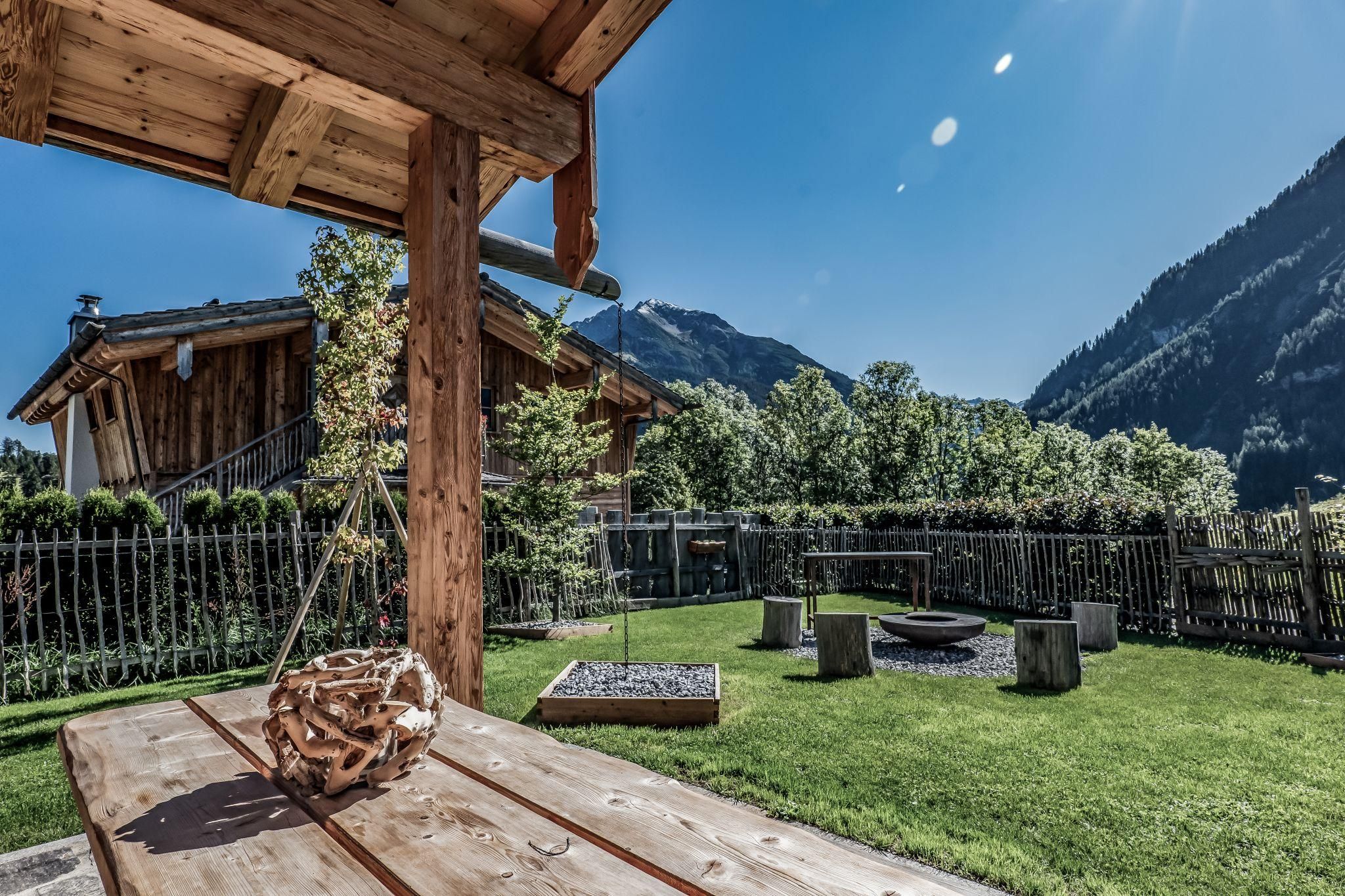 Ein schöner Garten mit einer Holzbank und Blick auf die Berge. Die Umgebung ist grün und lädt zum Entspannen ein.