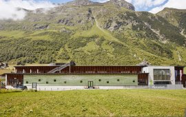 Zum Dorf hin &ouml;ffnet sich das Alpinarium Galt&uuml;r den Besucher:innen. Die m&auml;chtige Lawinenschutzmauer an seiner R&uuml;ckseite sch&uuml;tzt vor Naturgefahren vom Grieskopf.